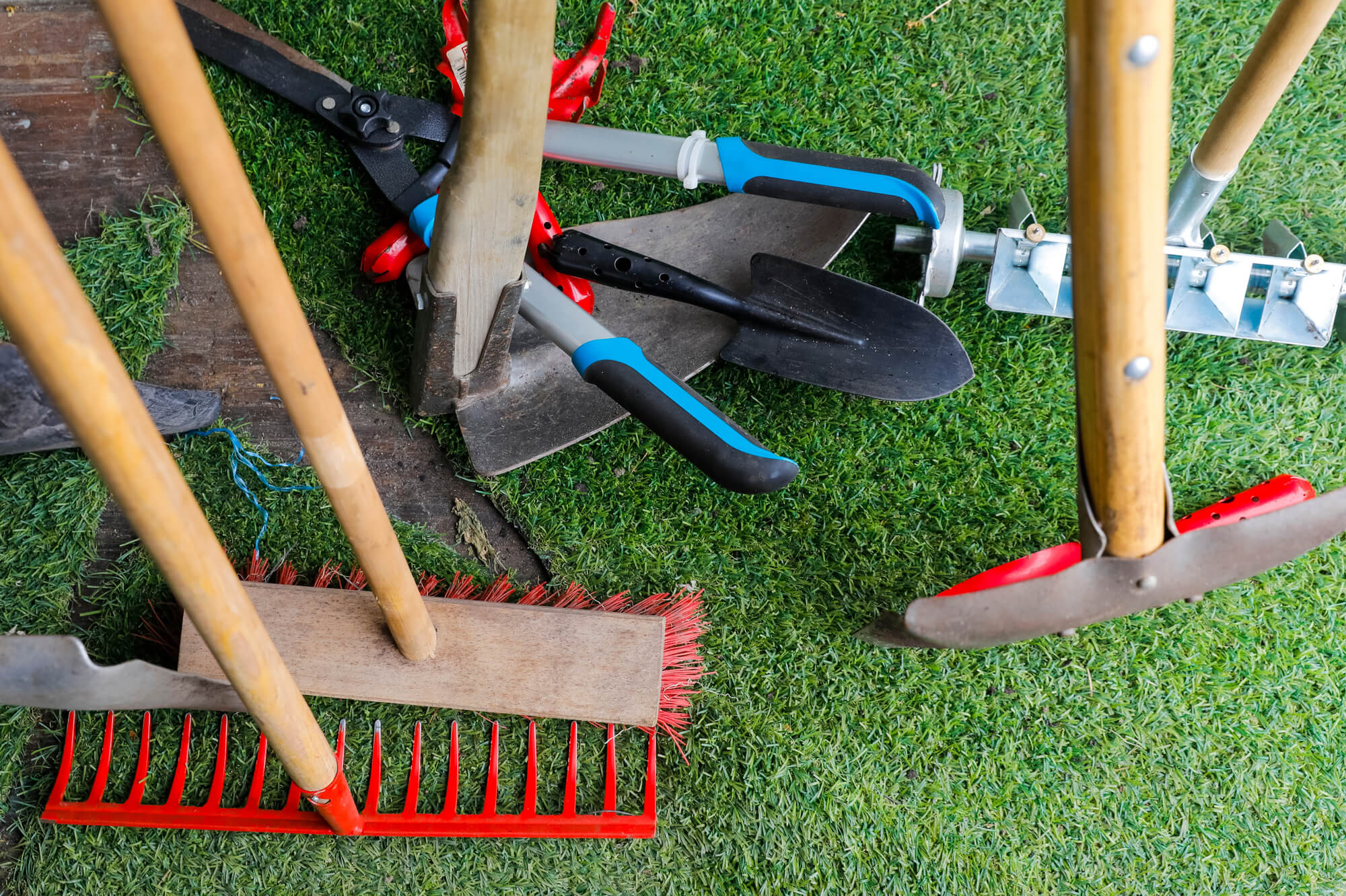 Verschiedene Gartenwerkzeuge liegen auf einem Rasen eng beieinander